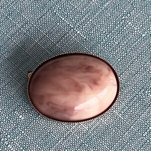 Oval pin brooch with pink bezel set stone in gold tone frame